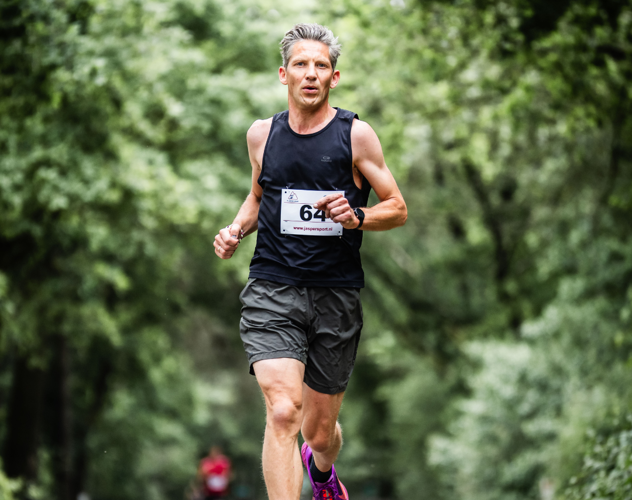 Hardloper Jacco rent op de weg onder bomen door